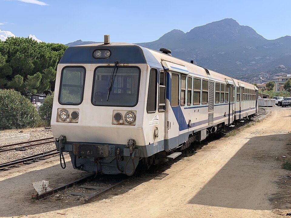 Un tren del Ferrocarril de Córcega en la estación, al pie de las montañas