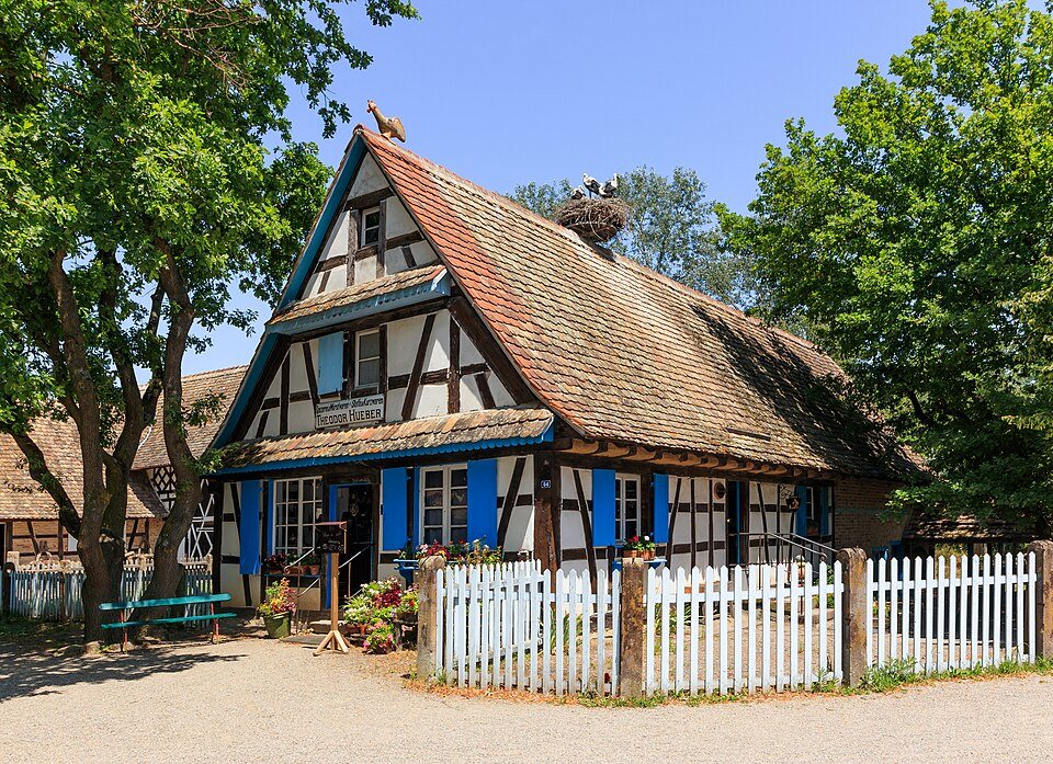 Ein elsässisches Fachwerkhaus mit weißem Zaun im Écomusée d'Alsace